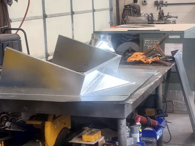 A galvanized roof cricket for a chimney taking shape on the fabrication bench.