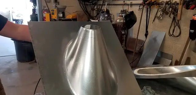 A smooth formed metal cone on a flat base plate — flashing for a pipe through a roof.