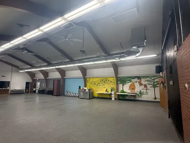 A long run of exposed spiral duct along the ceiling of a large community hall.
