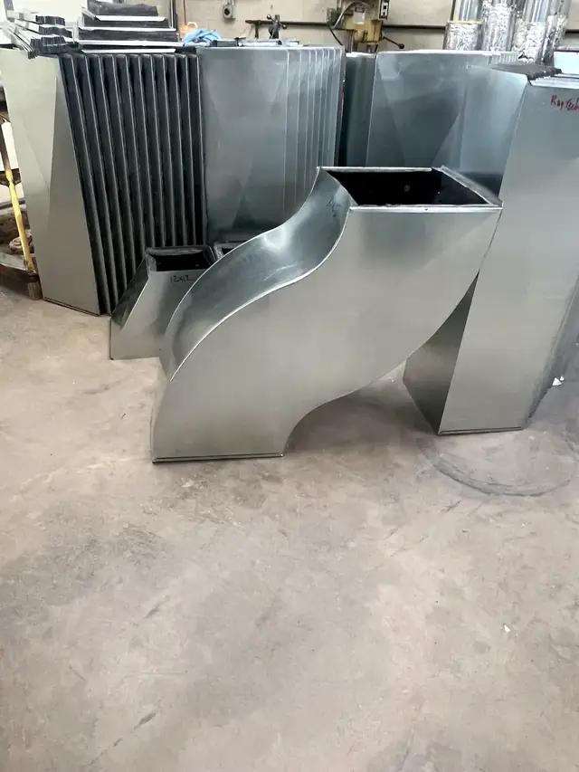 Galvanized offset transitions standing on the shop floor.