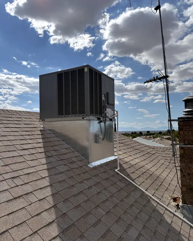 A new rooftop unit on a tall galvanized curb beside a TV antenna and brick chimney.