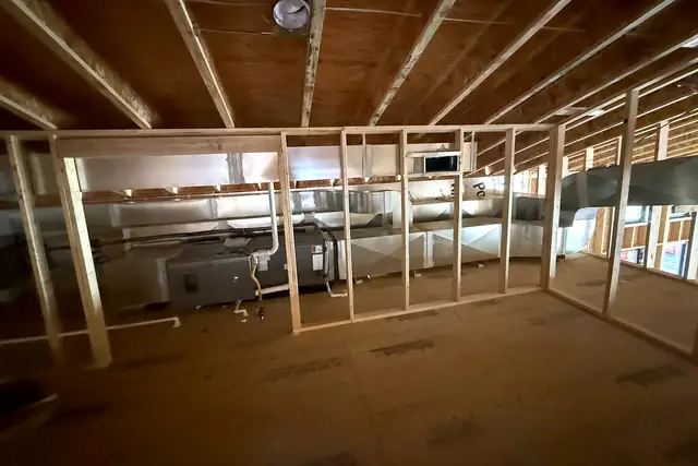 Duct and equipment roughed in behind fresh stud walls in a building under construction.
