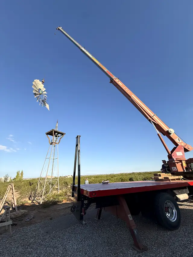 The Macias crane truck lifting a windmill head up beside its tower in the desert.